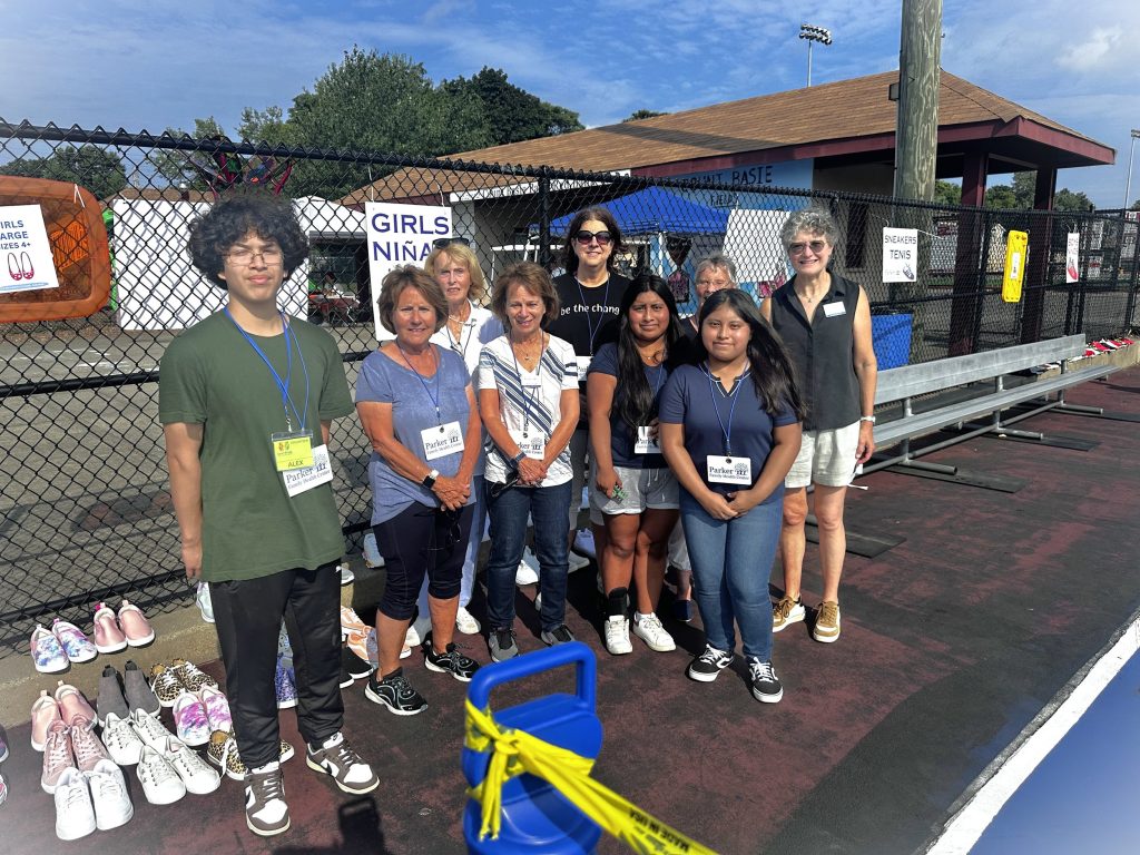 Volunteers beside rows of donated sneakers at an outdoor community event