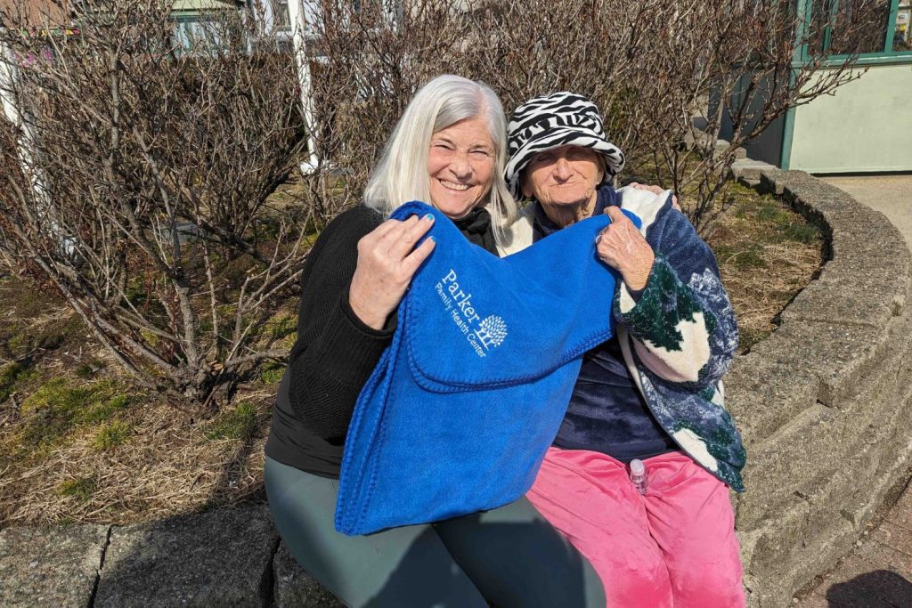 Two neighbors outdoors, one holding a blue Parker tote bag