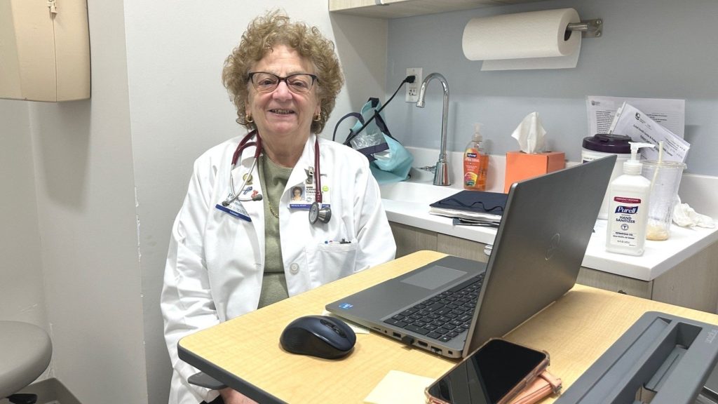 A volunteer physician at a laptop in an exam room