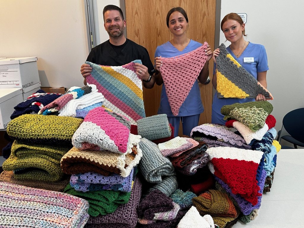 Clinic staff with handmade blankets donated by the Stitch Witches